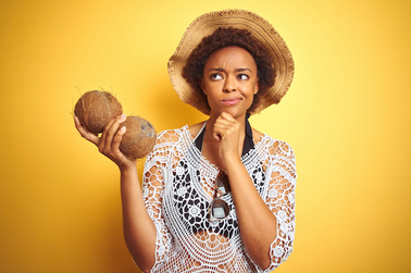 Woman holding two coconuts on a yellow background