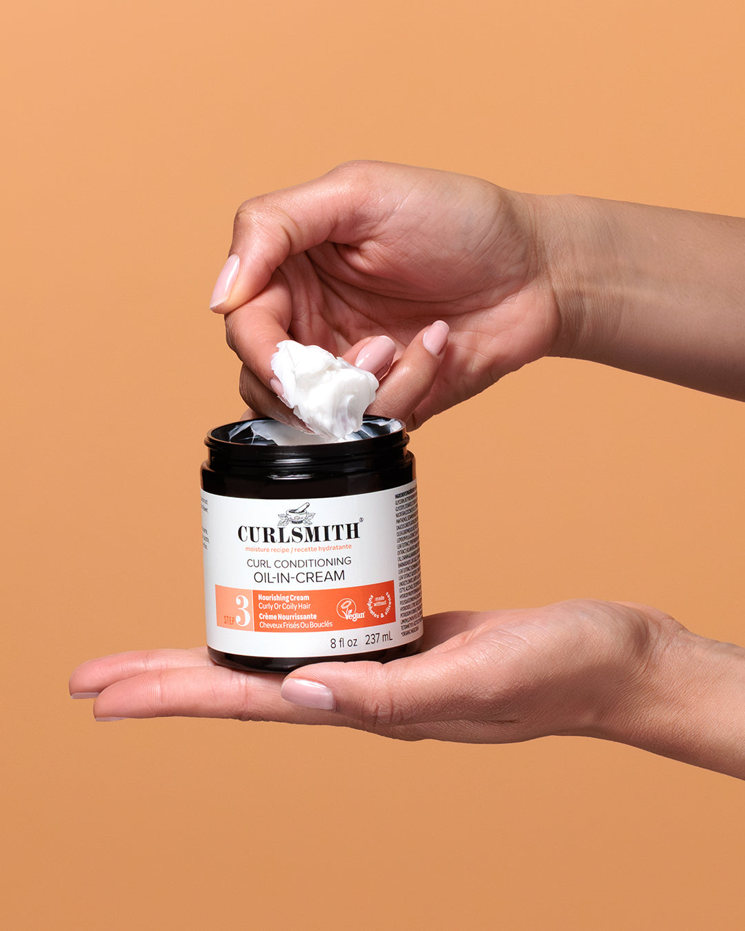 Person holding a jar of Curlsmith product with a brown background