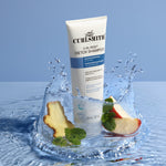 Curlsmith Curl Reset Detox Shampoo with apple slices and mint leaves on a water splash background