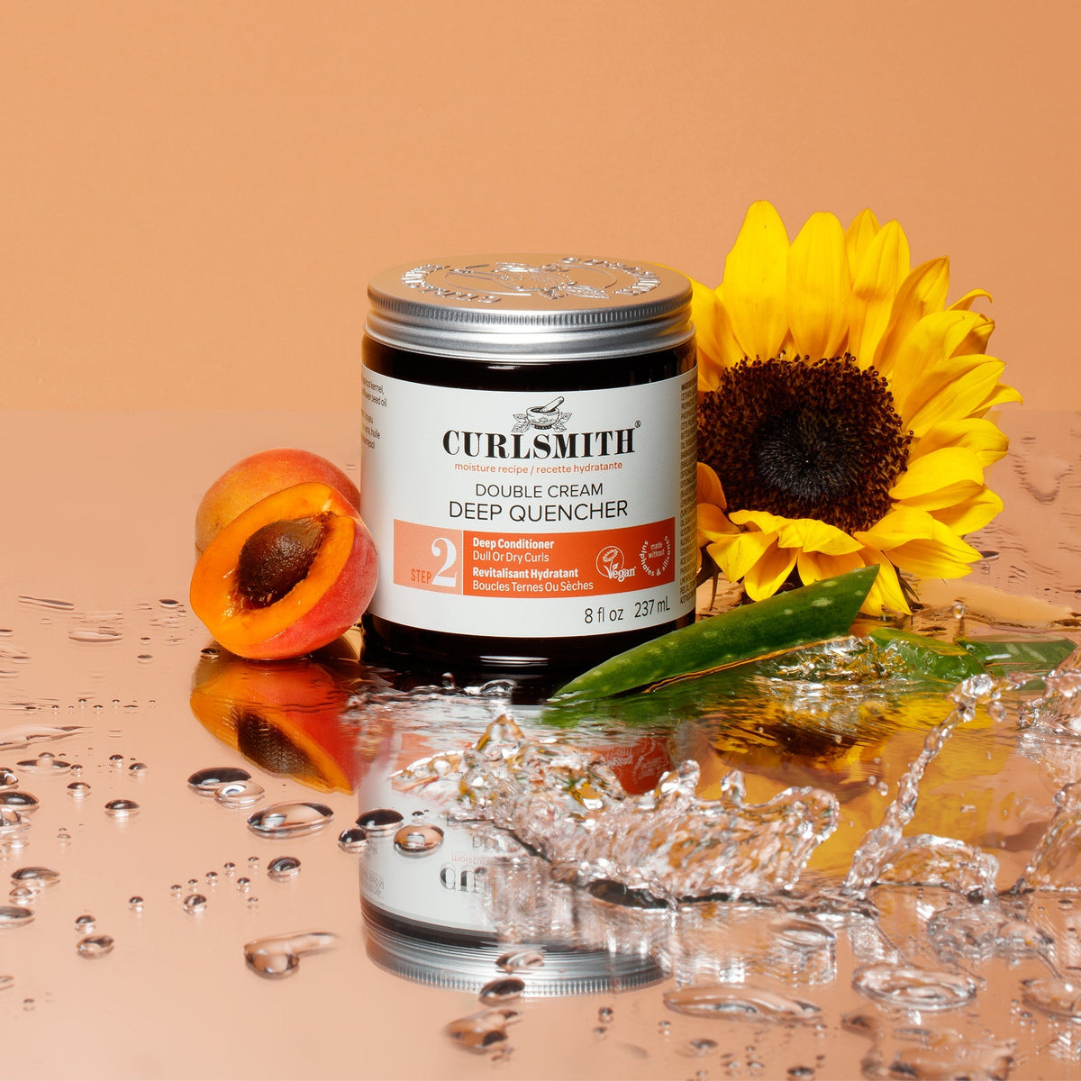 Curlsmith Double Cream Deep Quencher jar with a sunflower and apricot on a reflective surface.