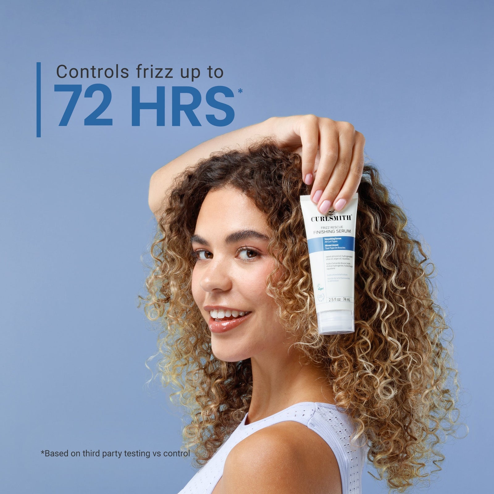 Woman with curly hair holding a bottle of hair product against a blue background