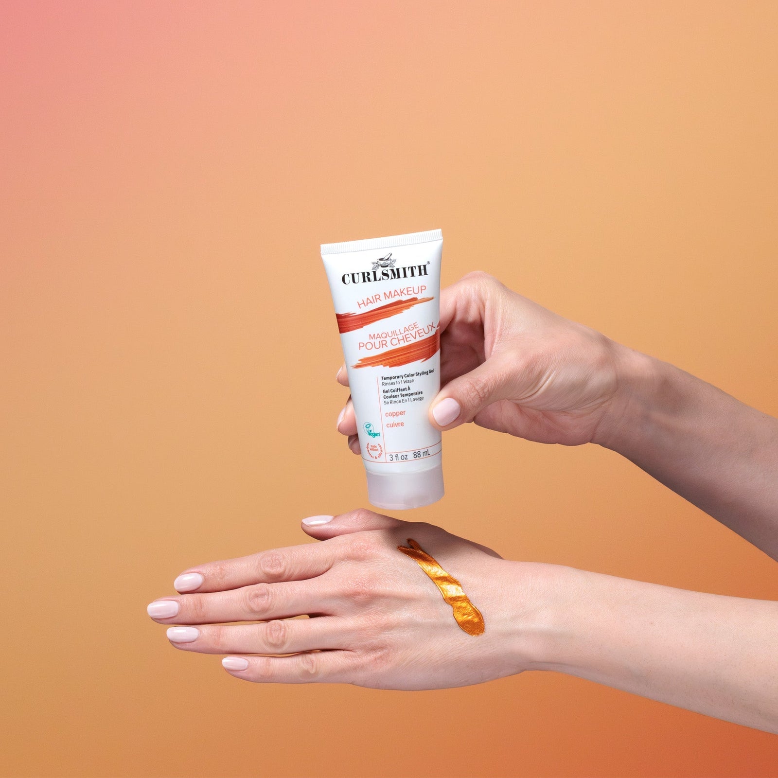 Hand holding a Curlsmith hair mask tube against an orange gradient background