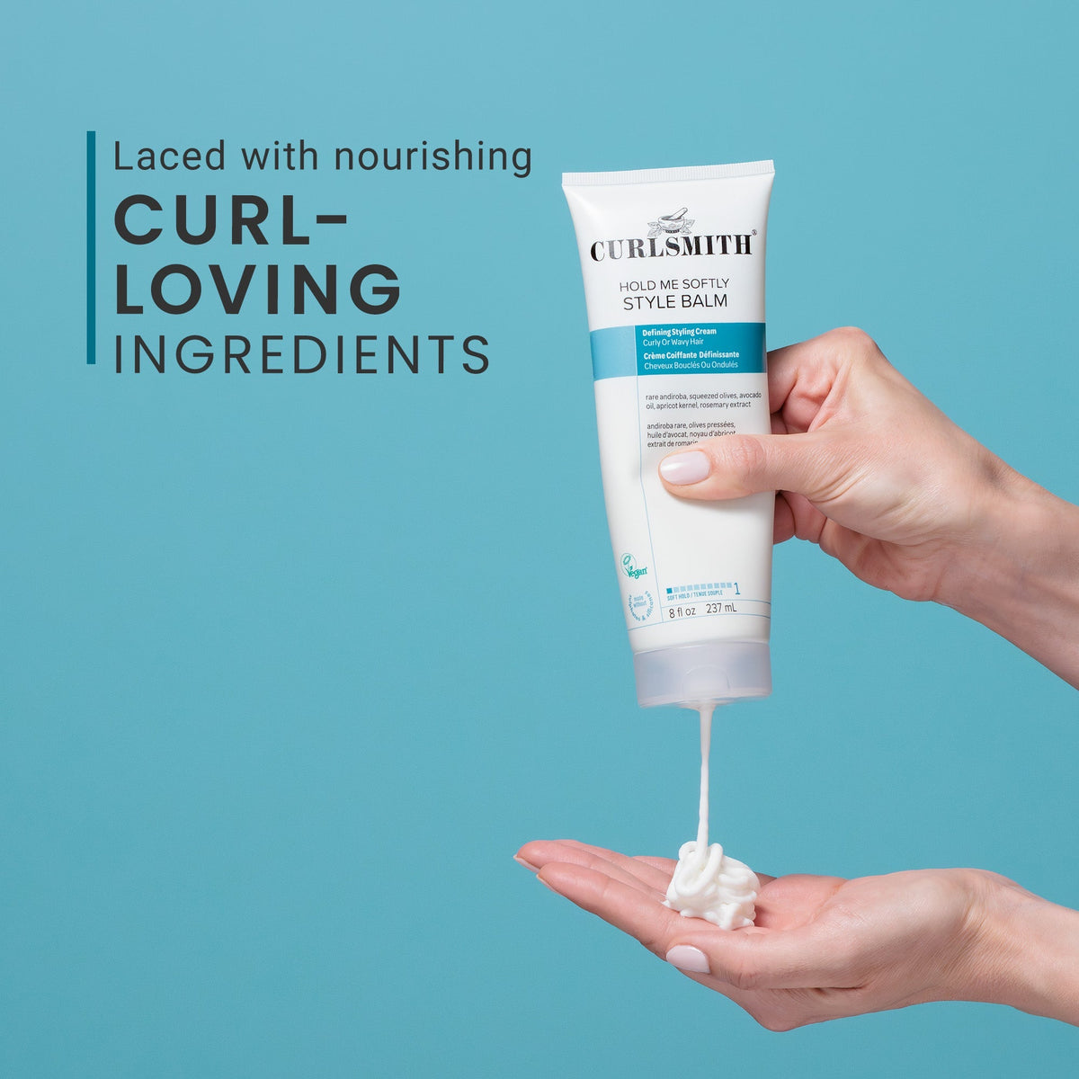Hand holding a tube of CurlySmith Style Balm with blue background